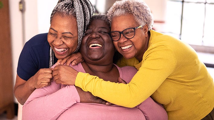 three black women smiling and hugging