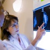 A female doctor examines a mammogram x-ray with her patient in a hospital setting.